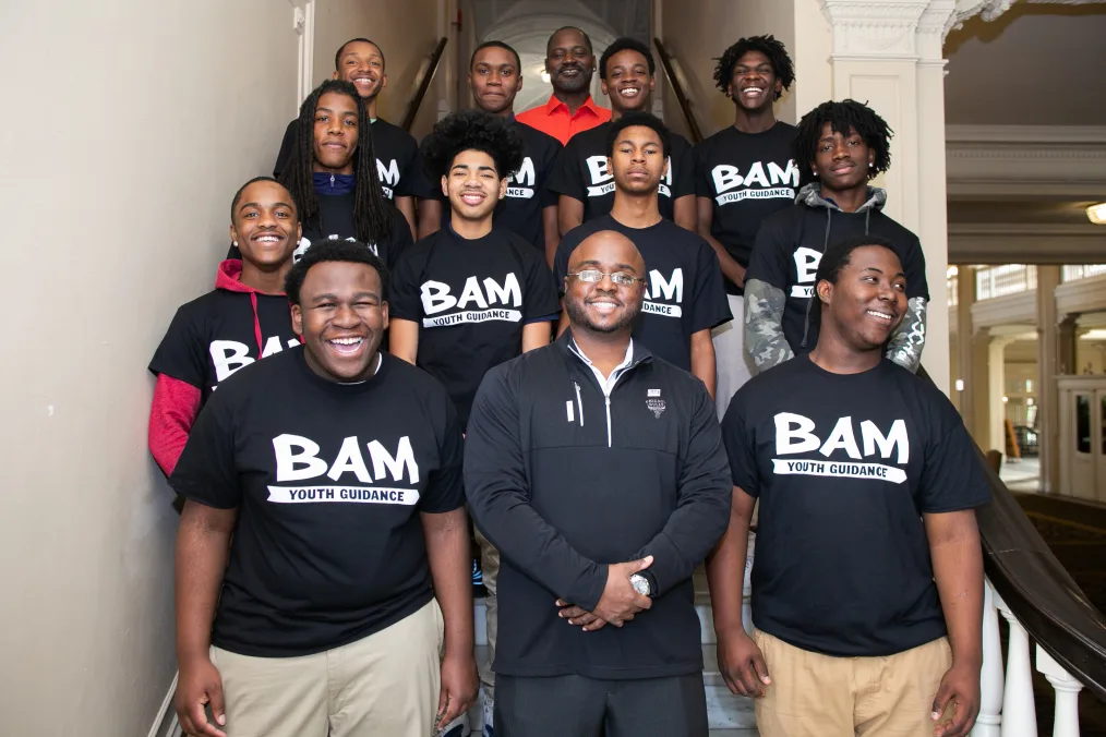A group of men wearing shirts that read "BAM" pose for a photo.