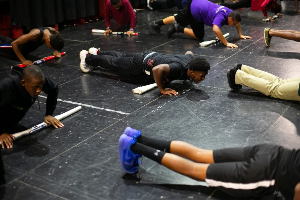 A group of young men do pushups as part of their drill team practice.