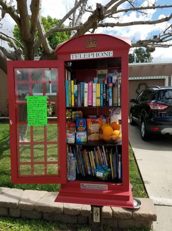 A red telephone booth is filled with books for people to take for free.
