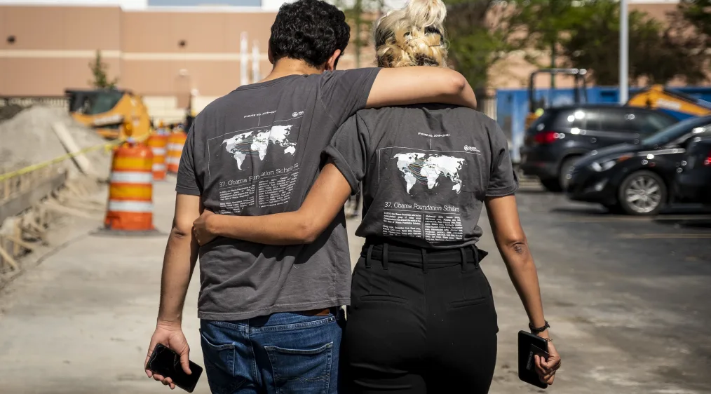 Two Obama Foundation Scholars walk away from camera with their arms around one another. They are wearing they're Obama Foundation Scholars swag!
