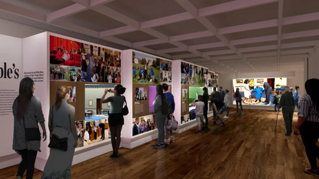 A rendering of a museum exhibit shows a wall full of photos from the Obama White House alongside scale models of East Wing Rooms and the South Lawn. People of varying skin tones look at the photos and models, some taking photos, others pointing.
