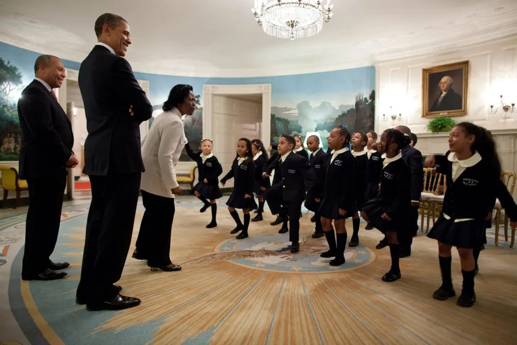 President Barack Obama and Massachusetts Gov. Deval Patrick listen as students from Orchard Gardens K-8 School in Roxbury, Mass., perform