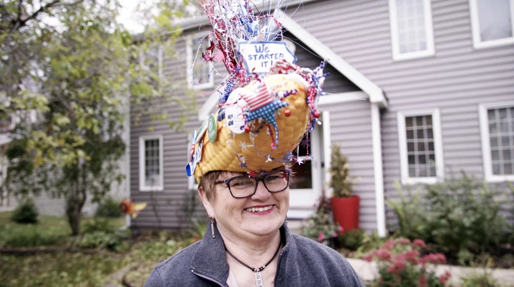 Nancy Bobo smiles to camera wearing her Obama corn hat.