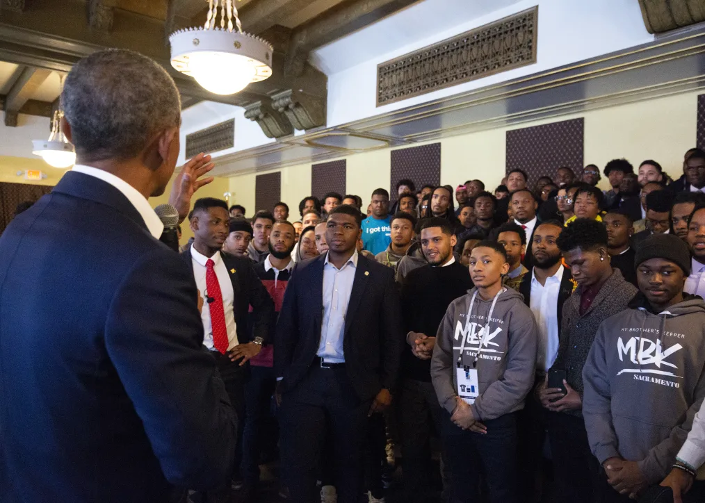 President Obama speaks to a group of young black men of various skin tones.