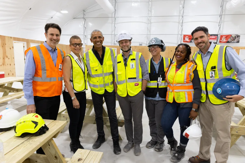 Dina Griffin stands next to President Obama and five others. All have light and light medium skin tones and are wearing safety vests. Some are wearing hard hats.