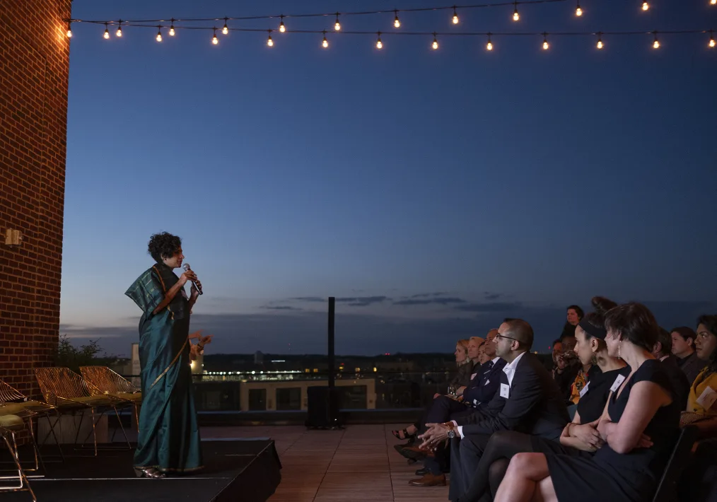 Obama Fellow Preethi Herman speaks to a group of people against a beautiful sunset.