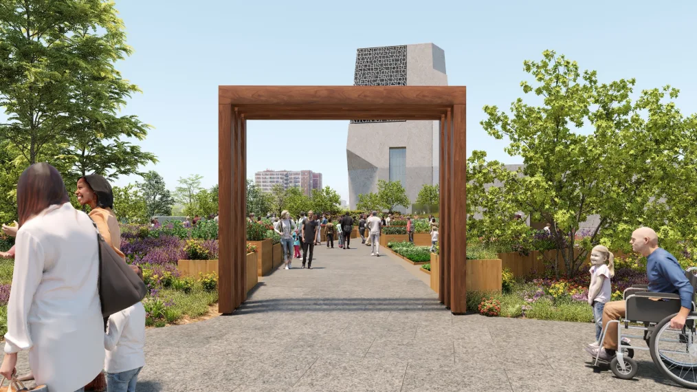 A rendering of the entrance of the Eleanor Roosevelt Fruit & Vegetable Garden at the Obama Presidential Center. The entrance is a large sqaure brown wood awning. Surrounding the awning are different plants, vegetables, and trees in green, purple, and pink. In the distance of the image is the Obama Presidential Center Museum Building. Arround the Garden are a variety of people walking and standing. 