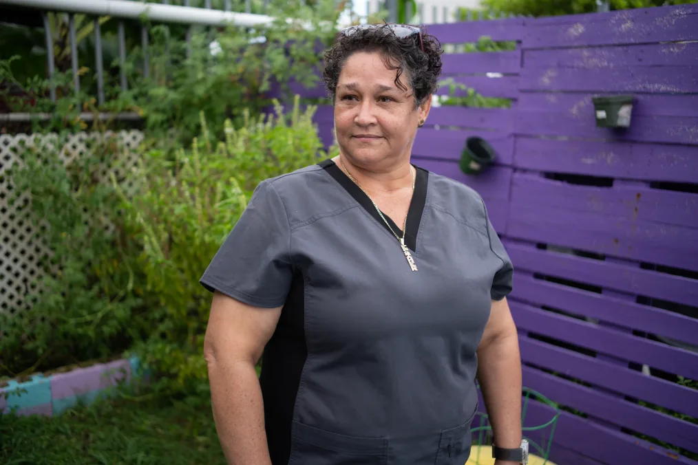 A woman with a medium-light skin tone takes a picture in a garden