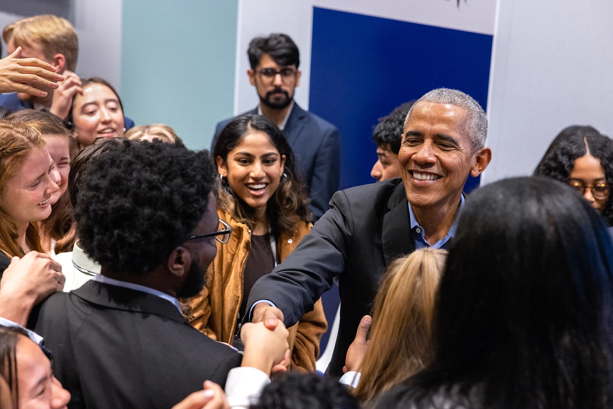 President Obama shakes hands over a crowd of young people with various skin tones. 