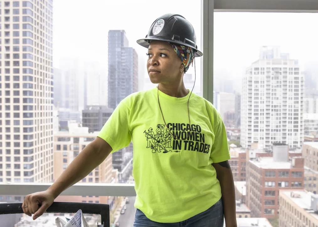 Zahrah Hill looks to the horizon wearing a hard hat a neon green shirt that reads "Chicago Women in Trades."