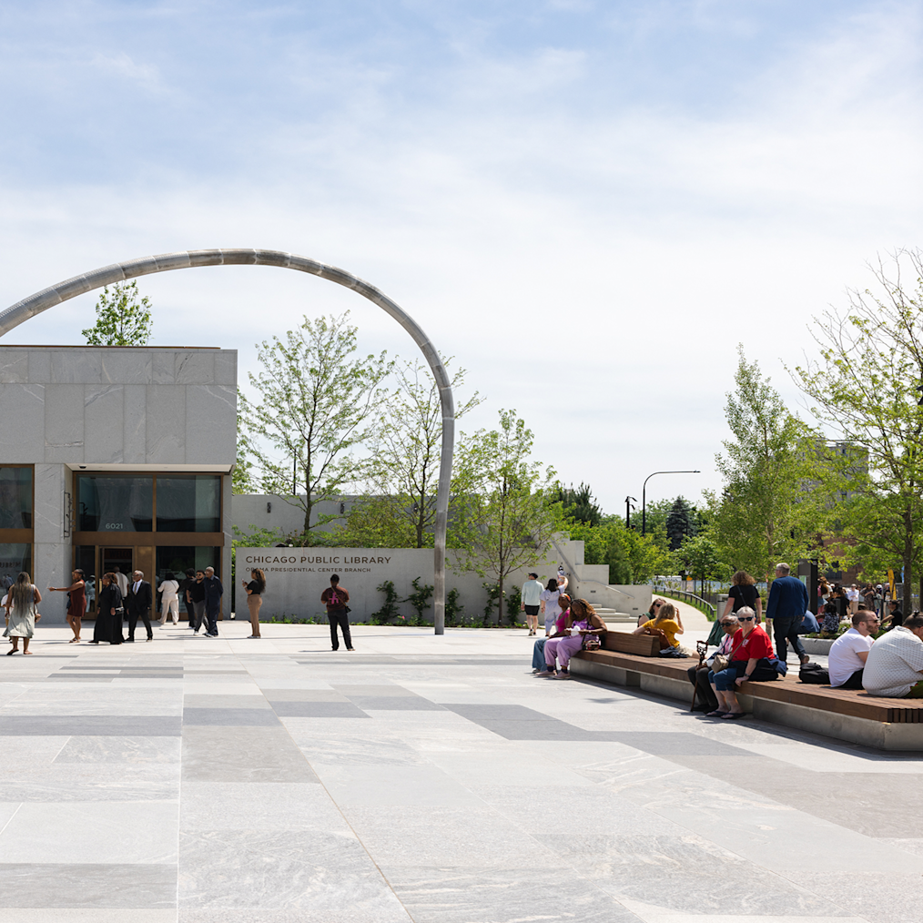 A rendering of people of all ages and skin tones gathering at several picnic tables on the John Lewis Plaza at the Obama Presidential Center.