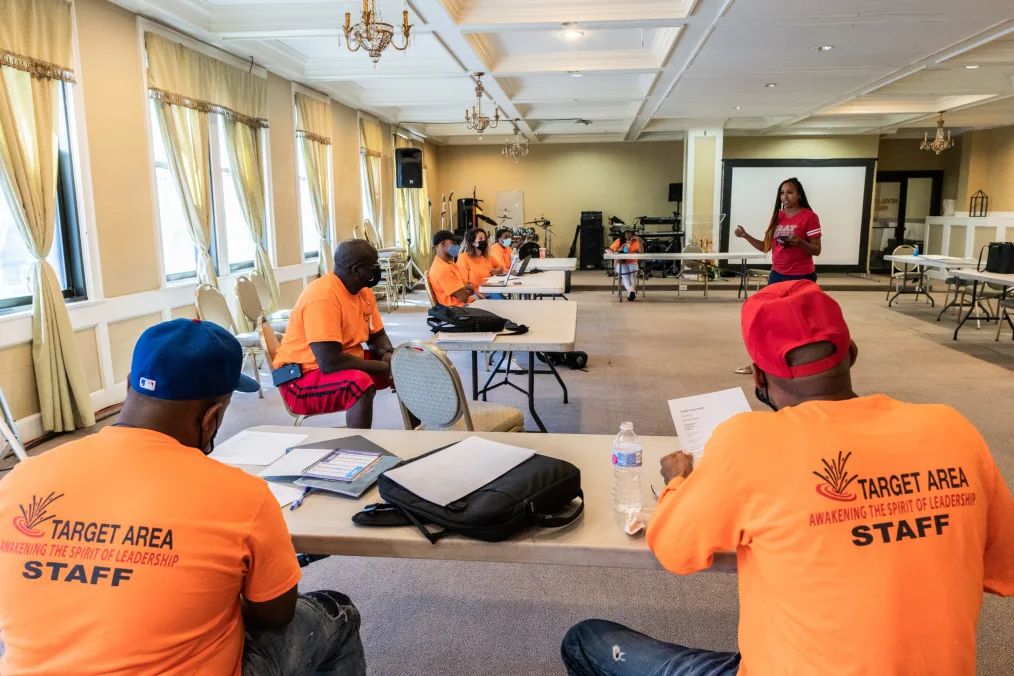 Pastor Tracey speaks to her team, who are all wearing bright orange shirts.