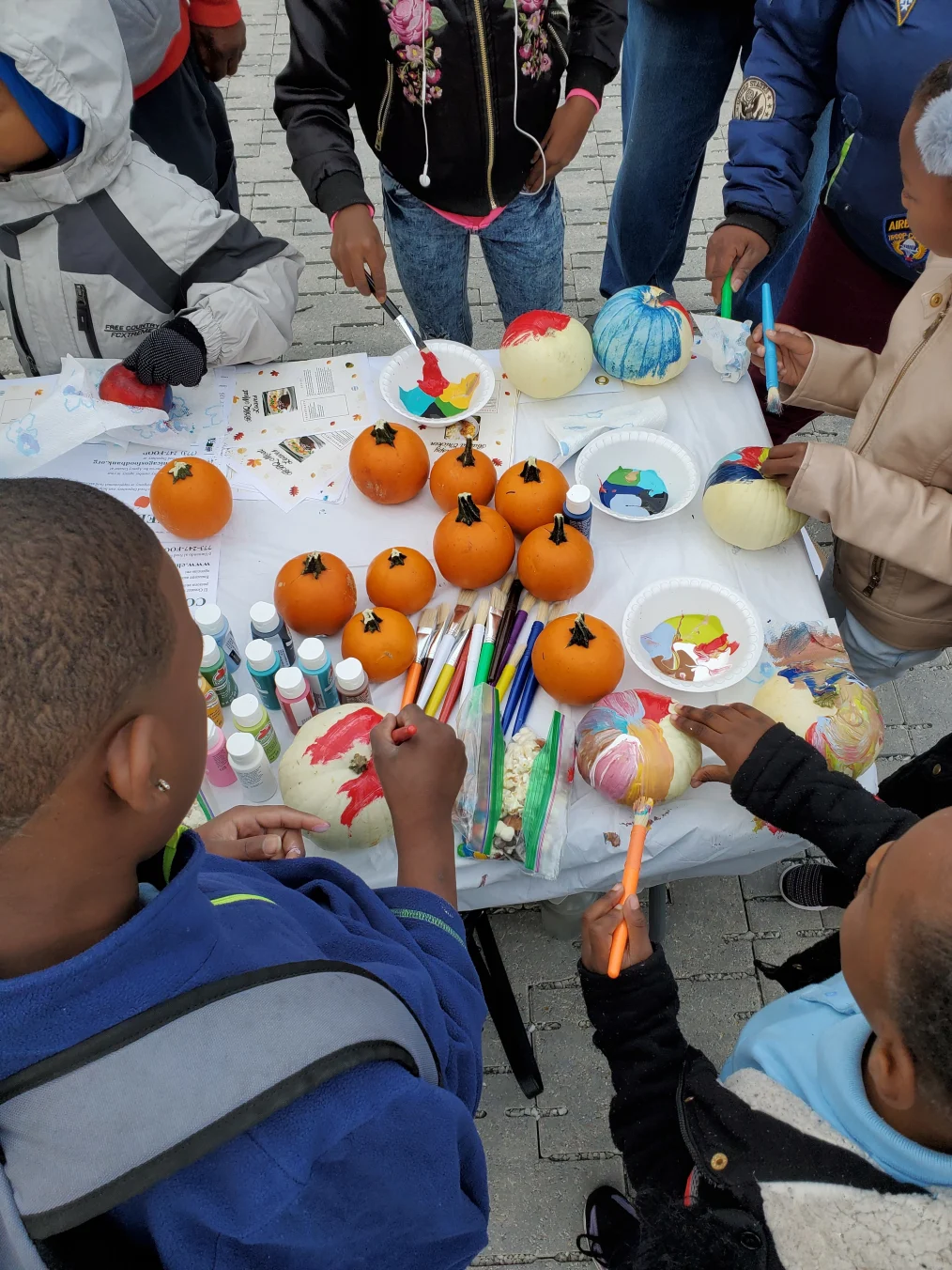 Kids with various skin tones painting pumpkins