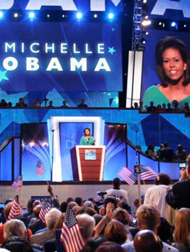  Michelle Obama stands at a podium in front of a crowd 