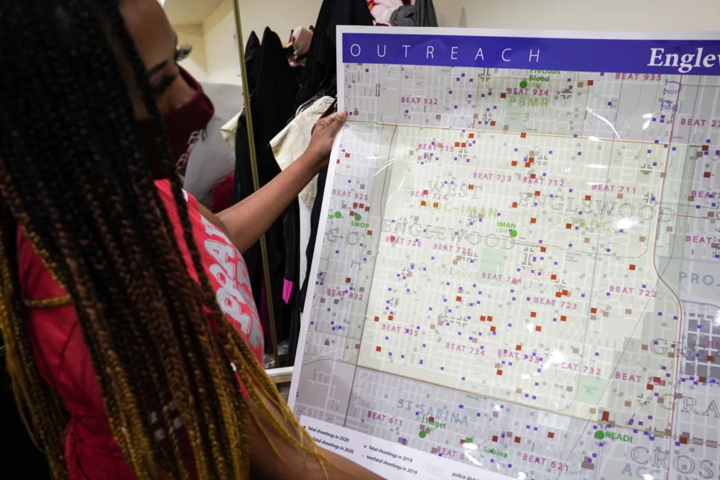 A woman holds up a map of the Englewood neighborhood of Chicago indicating where shootings have occurred.