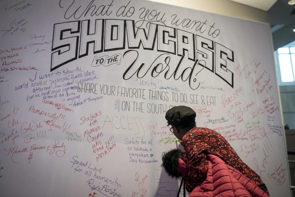 A woman writes on a South Side Showcase installation at an Obama Foundation public meeting.