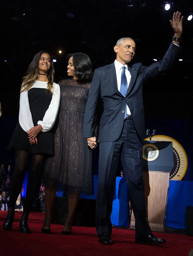 President Obama stands on stage with his wife and one of his daughters 