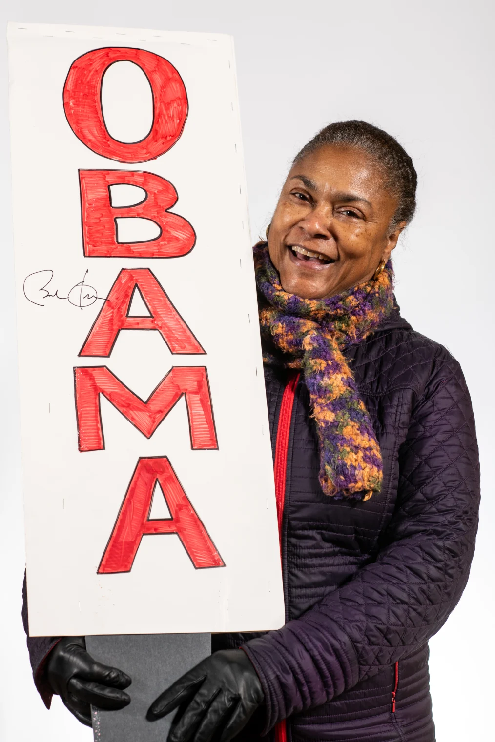Kimberly Reed smiles to camera holding a homemade sign that was autographed by President Obama.
