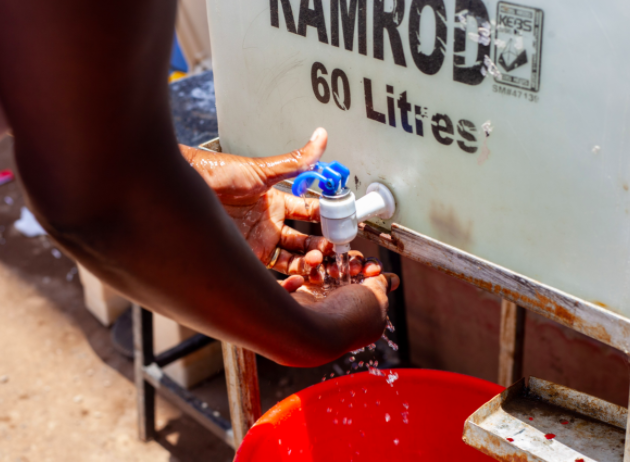 A person's hands are shown as they wash them at a hand washing station that Kennedy Odede set up.
