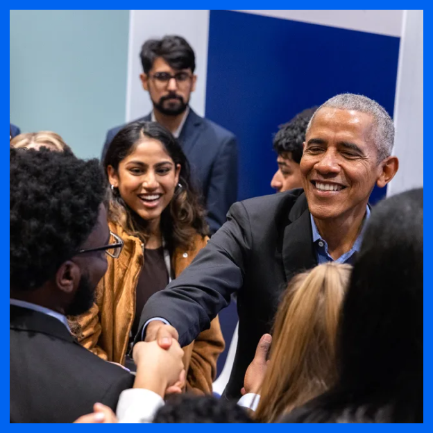 President Obama shakes hands over a crowd of young people with various skin tones. 