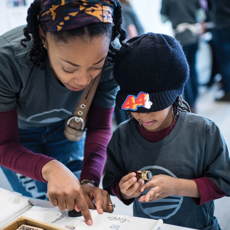 A woman shows a little girl where to place an item.