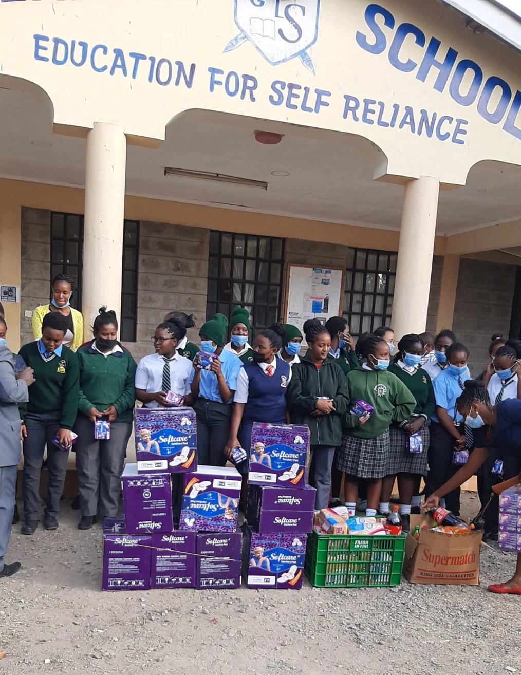 A group of students gather with supplies in front of their school.