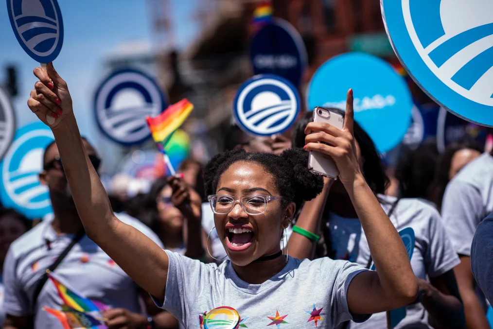 A young woman cheers with her arms in the air marching in the Chicago Pride Parade.
