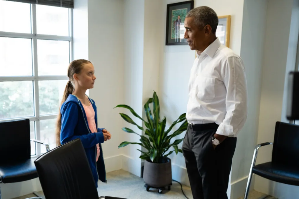 President Obama talks to a young girl with a light skin tone who is wearing a pink shirt and a blue hoodie.