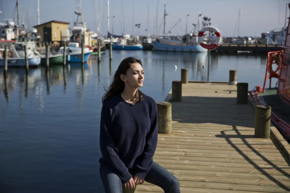 The sun hits Nima Tisdall’s face as she sits on a dock.