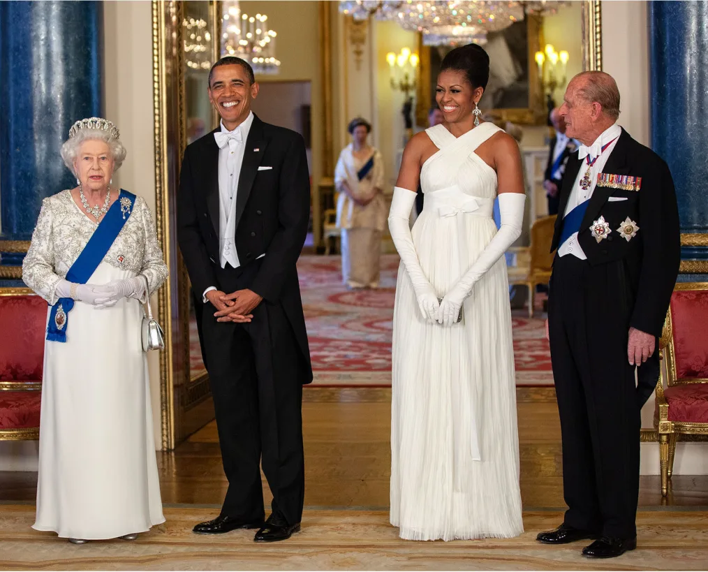This portrait shows President Obama, First Lady Michelle, Queen Elizabeth II, and Prince Phillip 
dressed in very formal attire smiling and posing toward the camera.