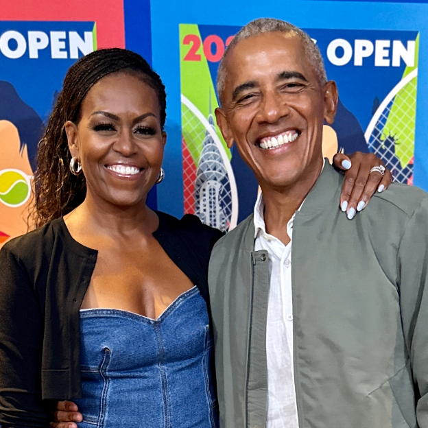 Mrs. Obama and President Barack Obama wearing casual clothing and posing in front of colorful posters.