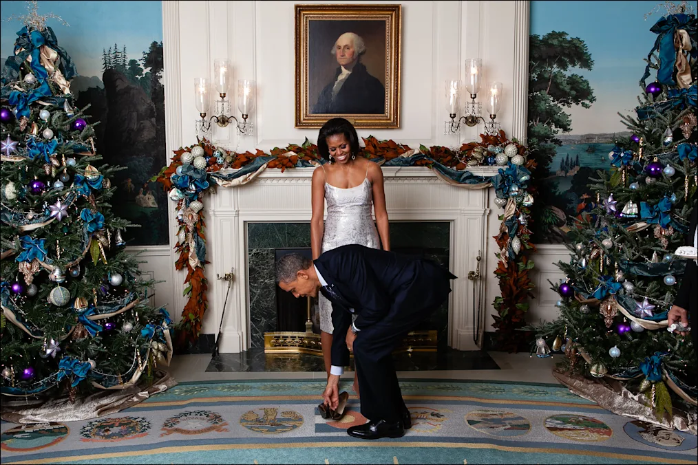 President Obama kneels to pick up the heels of Mrs. Obama following the Christmas Holiday Press Reception #2 in the Diplomatic Reception Room of the White House, Dec. 9, 2011. (Official White House Photo by Chuck Kennedy)