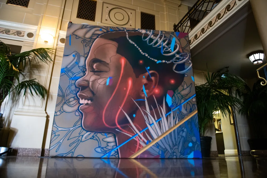A painted mural features the profile of a young black boy with red, blue, and white patterns.
