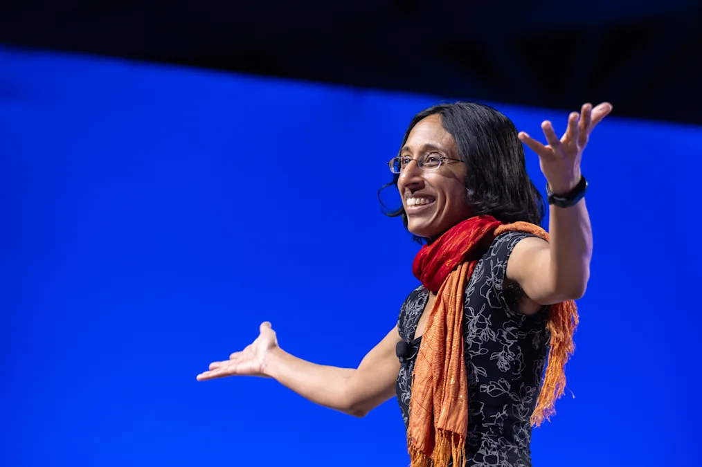 Finale Doshi-Velez speaks at the 2024 Democracy Forum. She has a medium skin tone and is wearing a red and orange scarf. 