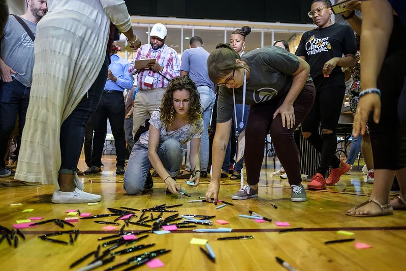 Two members pick up pens off the ground as part of a group activity.