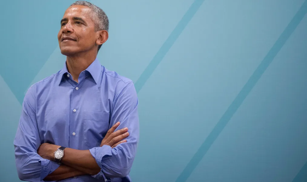 President Obama smiles with his arms crossed.