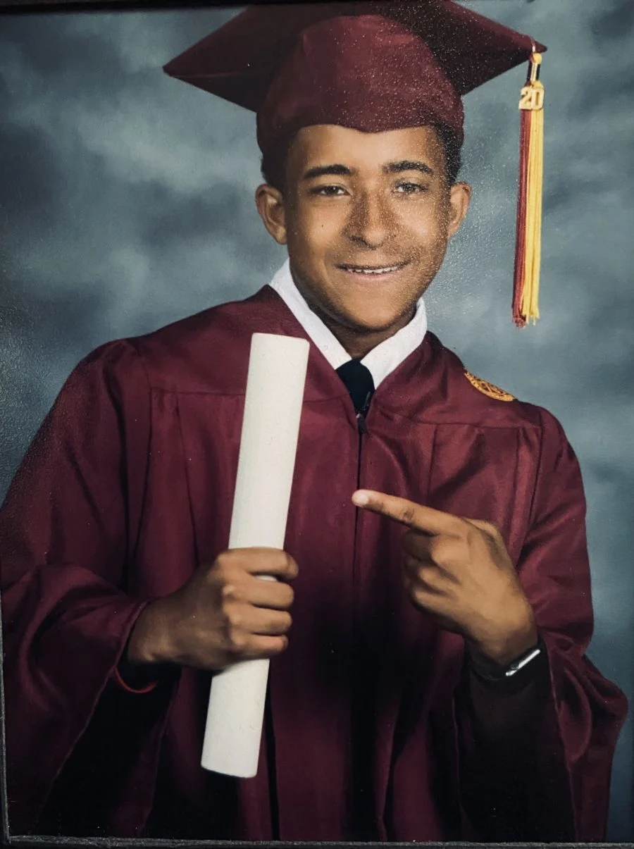 Santana Joseph Pruitt poses holding his diploma in a cap and gown.
