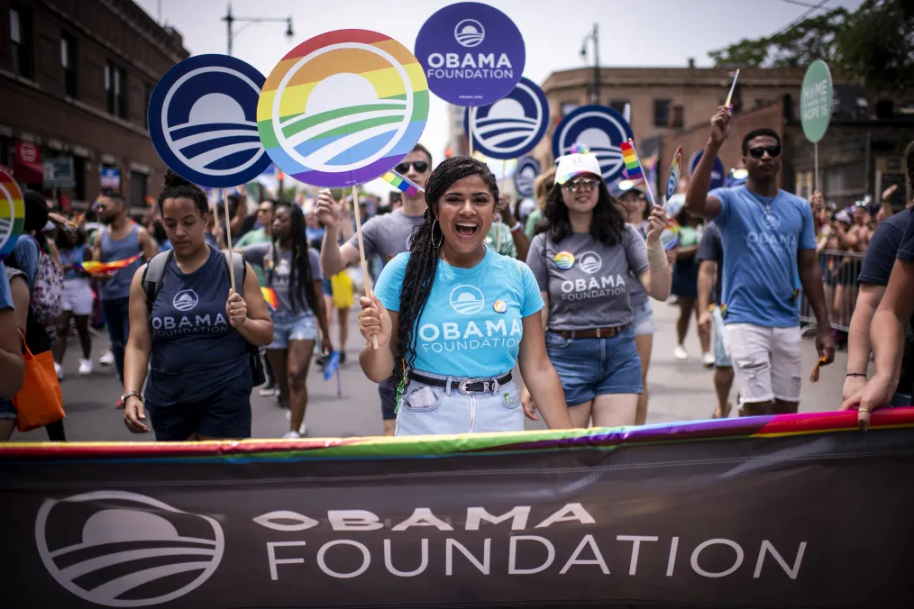 A woman smiles as she carries an Obama Foundation sign during the Chicago Pride Parade.