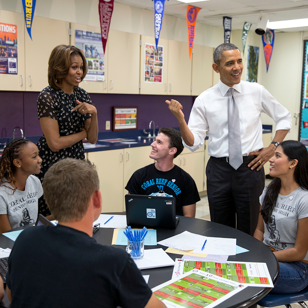 President and Mrs. Obama stand and chat with students at Coral Reed Senior High School. All are a range of light to dark skin tones. 
