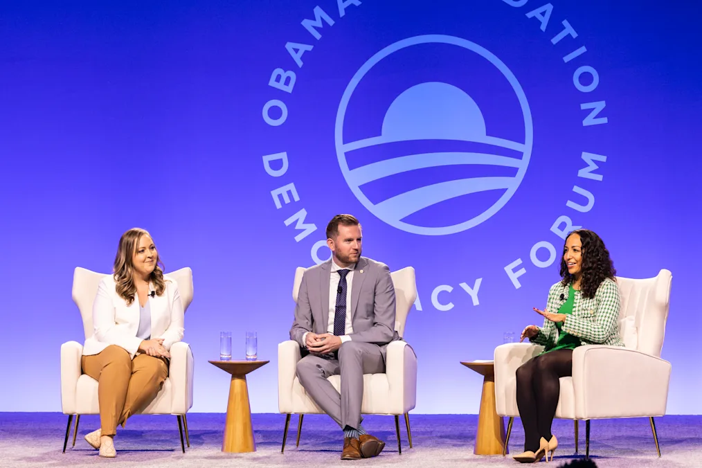 Kansas state Reps. Brandon Woodard and Tory Marie Blew, and Layla Zaidane have a conversation on stage. All are dressed professionally and have a range of light and medium skin tones. 