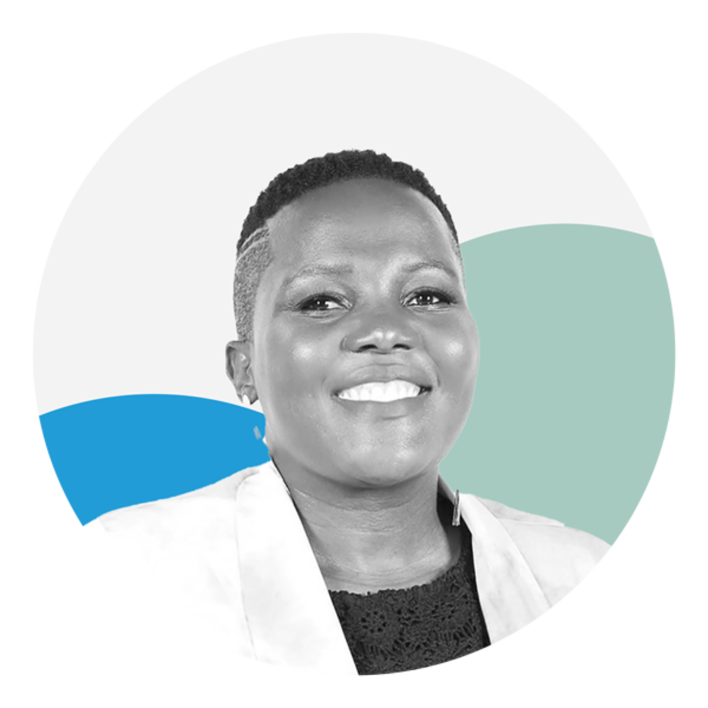 A Black woman with short cut hair is facing the camera smiling with her teeth showing. She is wearing a white Blazer with a black blouse. The photo is black and white and the background features two circles, one which is blue and the other green. 