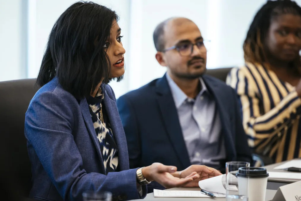 This picture shows a woman with a medium skin tone with short black hair, a man with a medium skin
tone, and another woman with a deep skin tone presumably at a meeting table discussion.