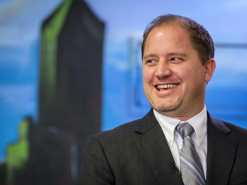 A man wearing a suit smiles to and looks to the  left.