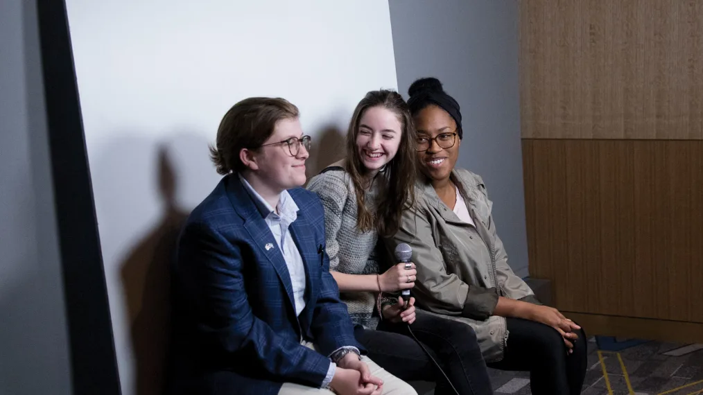 Two young women and one young man smile at one another while having their photo taken at a Foundation event.