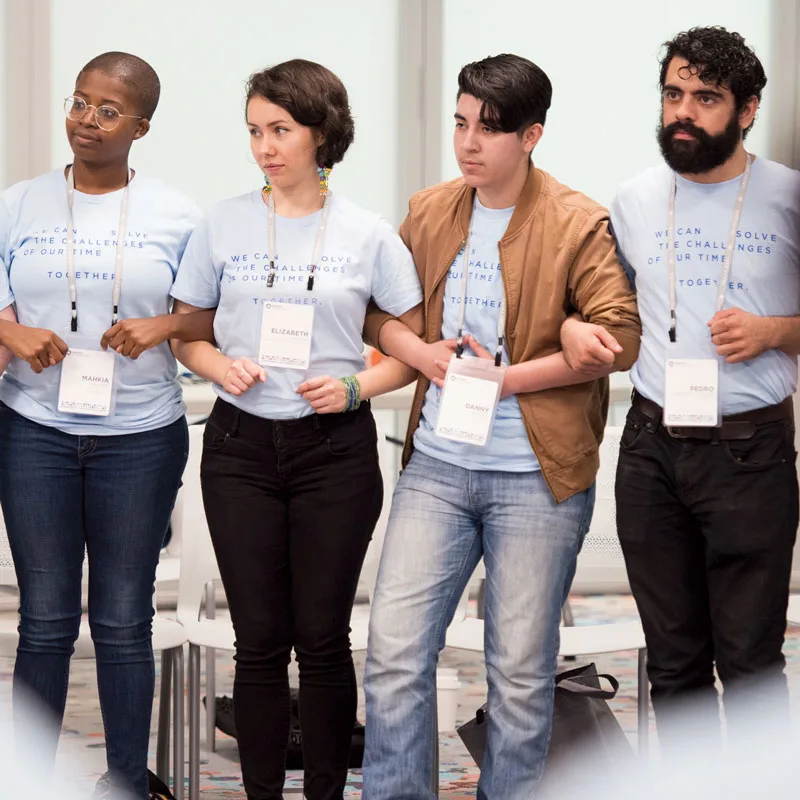 Four young people lock arms during an Obama Foundation Community Leadership Corps kickoff event in 2018.