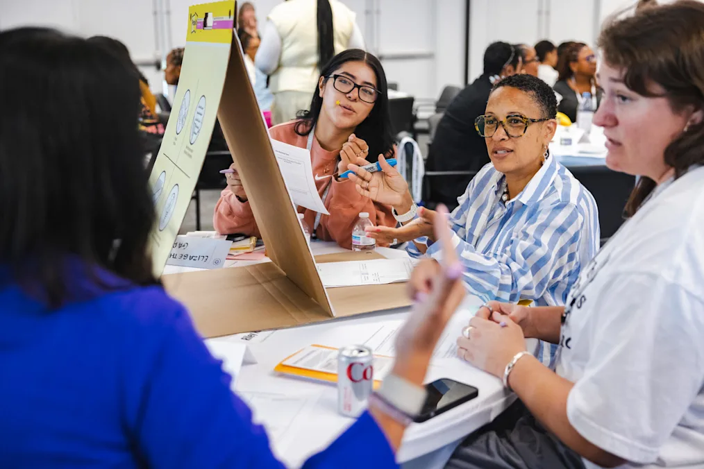 A group of women with a range of light to dark skin tones sit at a round table with large easel paper atop the table with notes. All are dressed professionally. In the background more groups of people sit around tables.​​​​‌﻿‍﻿​‍​‍‌‍﻿﻿‌﻿​‍‌‍‍‌‌‍‌﻿‌‍‍‌‌‍﻿‍​‍​‍​﻿‍‍​‍​‍‌‍​﻿‌‍﻿﻿‌‍﻿‍‌﻿‌​‌‍‌‌‌‍﻿‍‌﻿‌​‌‍‌‍‌﻿‌‌‌‍﻿​​‍﻿‍‌‍​﻿‌‍﻿﻿‌‍﻿‌​‍​‍​‍﻿​​‍​‍‌‍‍​‌﻿​‍‌‍‌‌‌‍‌‍​‍​‍​﻿‍‍​‍​‍‌‍‍​‌﻿‌​‌﻿‌​‌﻿​​‌﻿​﻿​﻿‍‍​‍﻿﻿​‍﻿﻿‌‍​‌‌﻿​​‌﻿​​​‍﻿‍‌‍​﻿‌‍﻿﻿‌‍﻿‍‌﻿‌​‌‍‌‌‌‍﻿‍‌﻿‌​‌‍‌‍‌﻿‌‌‌‍﻿​​‍﻿‍‌‍​﻿‌‍﻿﻿‌‍﻿‌​‍﻿﻿‌﻿​﻿‌﻿​​‌‍​‌‌‍​﻿‌‍‌‌‌﻿​﻿​‍﻿﻿‌‍﻿​​﻿‌﻿‌‍‍​​﻿‌‌​﻿‍‌‌‍‍​‌‍‌‍‌‍﻿‍‌‍﻿​‌﻿‍​‌‍‍‍‌﻿‍​​‍﻿﻿‌‍‌‌‌‍﻿‍‌﻿‌‍‌‍‍‌‌﻿​‍‌‍﻿﻿‌‍﻿‍‌‍﻿‌‌‍‌‌‌‍﻿‍‌﻿‌​‌﻿​﻿​‍﻿﻿‌‍﻿‌‌‍​‌‌﻿​﻿‌﻿‌​‌‍‌‌‌﻿​‍​‍﻿﻿‌‍‌‌‌‍﻿‍‌﻿‌​‌﻿​‍‌‍‍‌‌‍‌‌‌﻿​﻿​‍﻿﻿​﻿​‍‌﻿‌‌​﻿​​‌﻿​‌‌​‌﻿‌‌‍‍‌​‍​‌​﻿​‌﻿​‍‌​‌‌​﻿​‍‌​​‍‌​﻿​‌​​‌‌​‌﻿‌‌‌‍‌‍‍﻿​﻿​‌‌​‍​​﻿‍‌‌‍﻿‍‌‌​﻿​‍﻿﻿​﻿﻿﻿‌‍‌‍‌‍﻿﻿‌‍​﻿‌﻿‌‌‌﻿​﻿‌‍‌‌‌‍‌​‌​‌‍‌‍‍‌‌‍‌‌‌‍﻿​‌‍‌​​﻿﻿‌‌‍​‌‌‍﻿​‌﻿‌​‌‌‌​‌‍‌‌‌﻿‍​‌﻿‌​​‍‌‍‌‍‌‍‌‍﻿﻿‌‍​﻿‌﻿‌‌‌﻿​﻿‌‍‌‌‌‍‌​‌​﻿​‌‍﻿﻿‌‍​﻿‌‍​‌‌‍﻿​‌‍‌‌​﻿﻿‌‌‍‌‌‌‍﻿‍​‍﻿‌‌‌‌‌‌‌​﻿​‍‌‍‌﻿​﻿‌‍﻿﻿‌﻿‌‌‌﻿​‍‌‍​﻿‌‍‌‌​﻿﻿‌‌﻿‌‍‌‍‌‌‌﻿​‍‌‍​﻿‌‍‌‌‌‍﻿​​‍﻿‌‌‍​﻿‌‍﻿﻿‌‍﻿‍‌﻿‌​‌‍‌‌‌‍﻿‍‌﻿‌​​‍﻿‌‌‍﻿​‌‍‍‌‌‍﻿‍‌‍‍﻿​‍​‍​‍﻿​​‍​‍‌‍​﻿‌‍﻿﻿‌‍﻿‍‌﻿‌​‌‍‌‌‌‍﻿‍‌﻿‌​‌‍‌‍‌﻿‌‌‌‍﻿​​‍​‍​﻿‍‍‌﻿‍﻿​‍​‍‌‍‌‌‌‍‌​‌‍‍‌‌﻿‌​‌‍﻿﻿‌﻿​‍‌​‍‌‌‍﻿‍‌﻿‌​‌‍‌‌‌﻿​‍‌‍‌‍‌‍​‌‌‍​﻿‌‍‌‌​‍​‍​﻿‍‍‌﻿‍﻿​‍​‍‌﻿‌﻿‌‍‍‌‌‍‌​‌‍‌﻿‌‍‌‌‌﻿‌​‌​‍‌‌‍‌​​‍​‍​﻿‍‍​‍​‍‌‍﻿‌‌﻿‌‌‌‍﻿​‌﻿‌​‌‍‍‌‌﻿​​‌‍﻿​‌‍‌‌‌​﻿​‌‍‍‌‌‍﻿‍‌‍‌‌​‍​‍​‍﻿​​‍​‍‌﻿‌﻿‌‍‍‌‌‍‌​‌‍‌﻿‌‍‌‌‌﻿‌​‌​﻿‍‌‍​‌‌‍﻿‌‌‍‌‌‌﻿​﻿‌﻿​​‌‍​‌‌‍​﻿‌‍‌‌​‍​‍​﻿‍‍​‍​‍‌‍​‍‌﻿‌‌‌‍‍‌‌‍﻿​‌﻿‌​‌‍‍‌‌‍﻿‍​‍​‍‌﻿﻿‌​‍﻿​​‍​‍‌‍‌‍‌‍‍‌‌‍‌‌‌‍﻿​‌‍‌​‌‌‌​‌﻿‍‌‌﻿​​‌‍‌‌​‍​‍​﻿‍‍​‍​‍‌‌‌​‌‍‌‌‌﻿‍​‌﻿‌​​‍​‍‌﻿﻿‌‌﻿﻿‌
