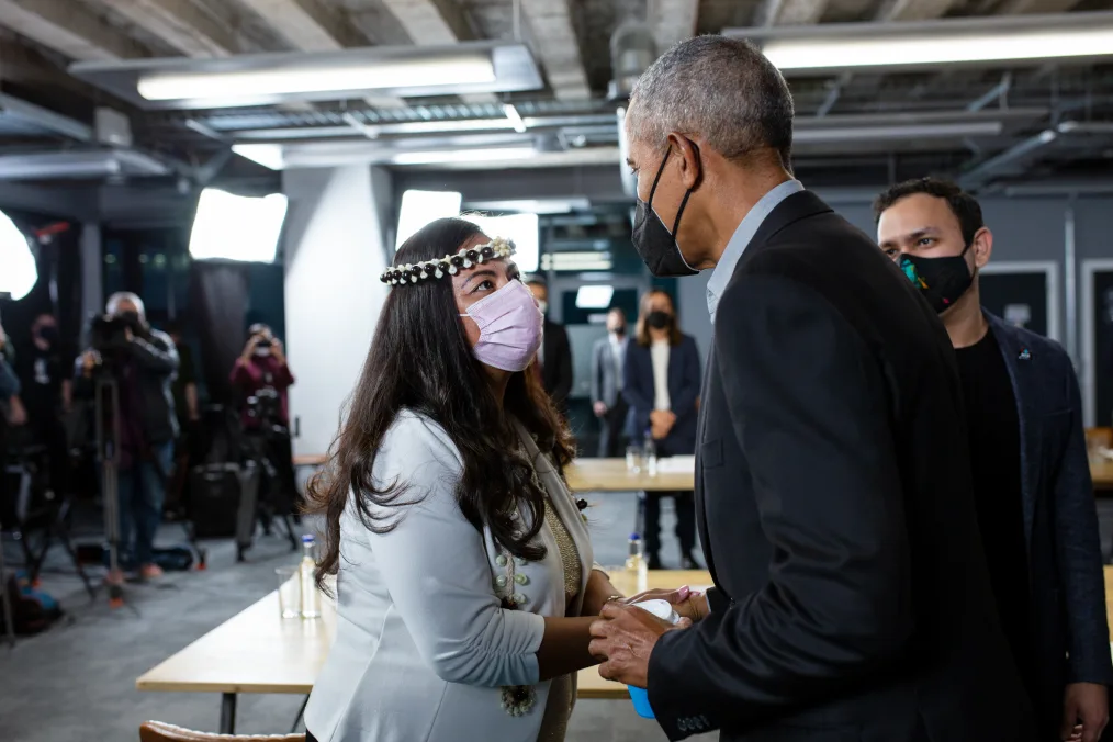 Sheila Babauta wears a pink mask as she shakes hands with President Obama, who is wearing a black mask.