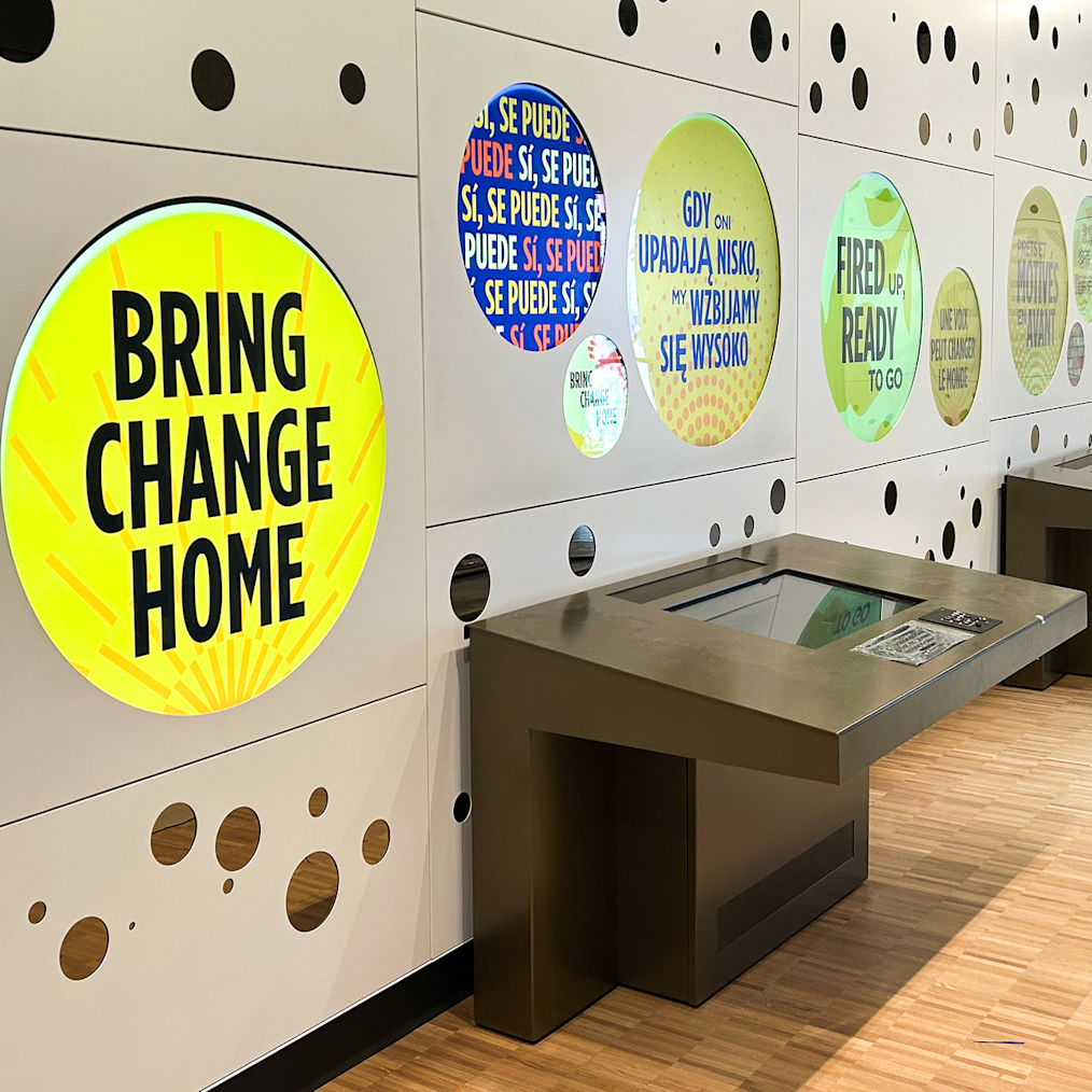 An image of “Yes You Can!” an interactive exhibit on Level 5 of the Obama Presidential Center Museum. There are several colorful makeshift buttons embedded into the walls. Below is a digital screen where visitors will have the opportunity to make their own buttons. 