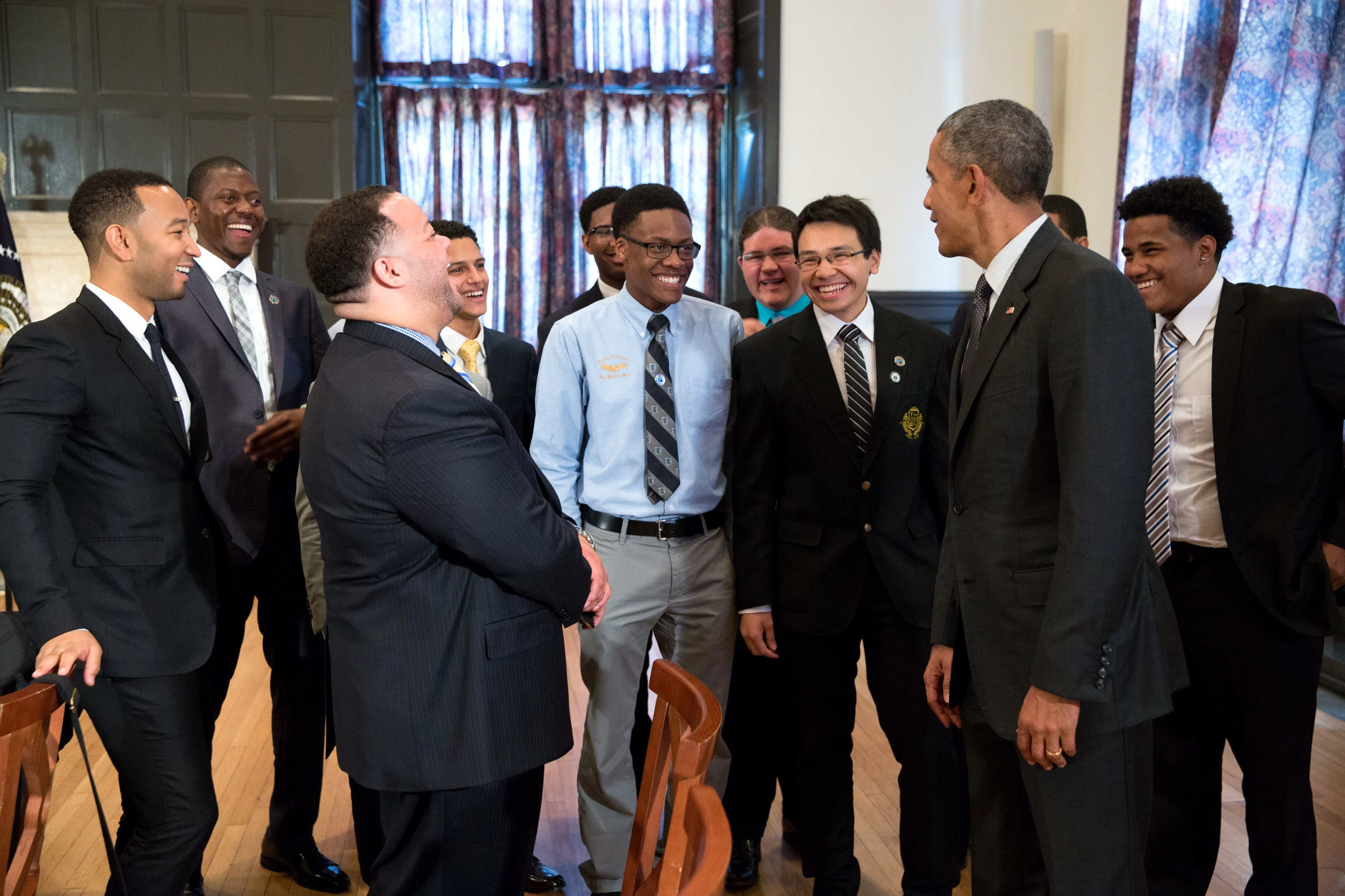 This picture shows President Obama in a room full of men wearing business professional clothes, 
laughing and smiling together.