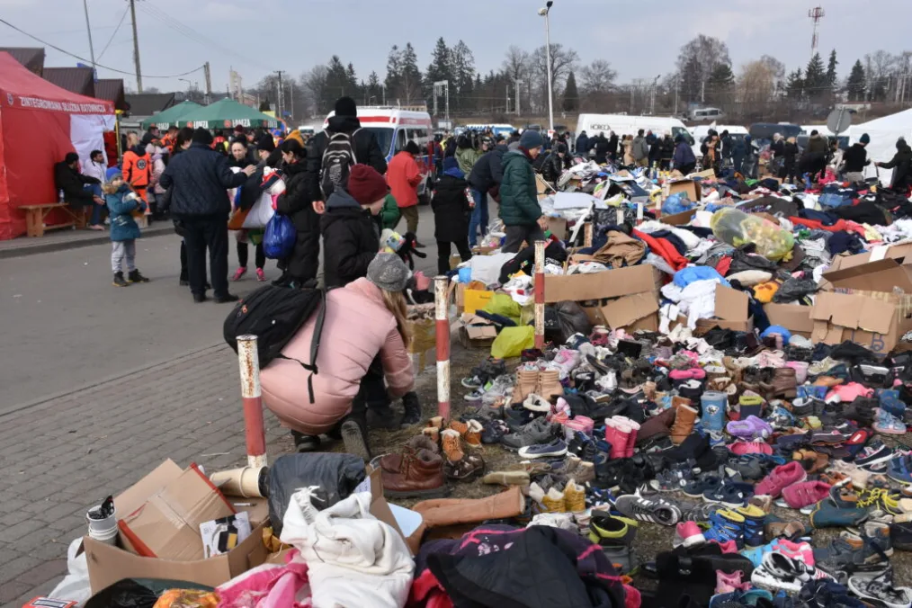A group of people gather around a smattering of bags and donated items in Poland.